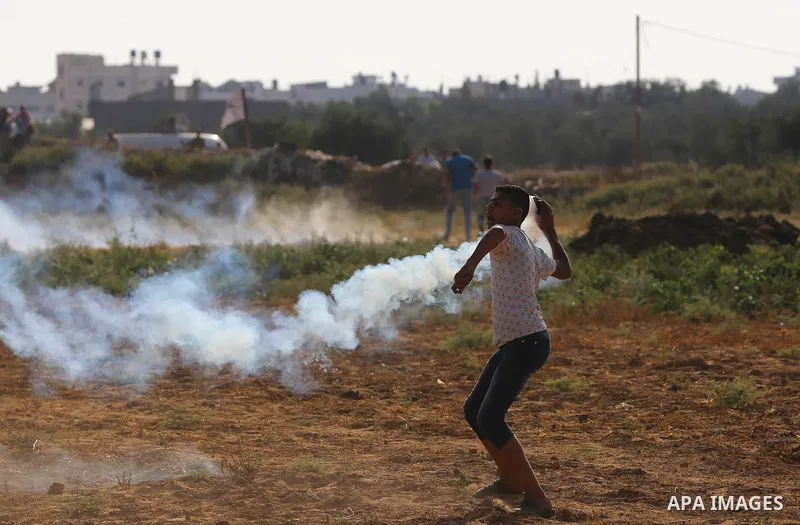 A Palestinian protester throws a tear gas canister towards Israeli security forces during clashes following a demonstration against the blockade on the Gaza Strip, near the border fence east of Jabalia refugee camp on Ju...