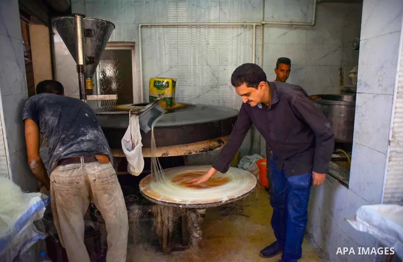 An Egyptian vendor prepares a traditional sweets known as "Konafa" on the Muslim holy fasting month of Ramadan at market in Cairo, Egypt, on June 10, 2017. Ramadan is sacred to Muslims because it is during that month tha...