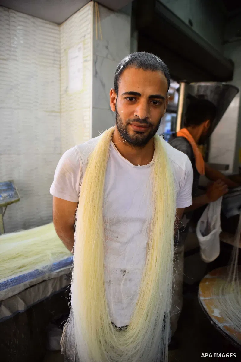 An Egyptian vendor prepares a traditional sweets known as "Konafa" on the Muslim holy fasting month of Ramadan at market in Cairo, Egypt, on June 10, 2017. Ramadan is sacred to Muslims because it is during that month tha...