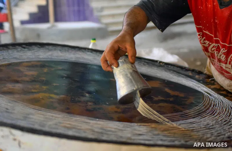 An Egyptian vendor prepares a traditional sweets known as "Konafa" on the Muslim holy fasting month of Ramadan at market in Cairo, Egypt, on June 10, 2017. Ramadan is sacred to Muslims because it is during that month tha...
