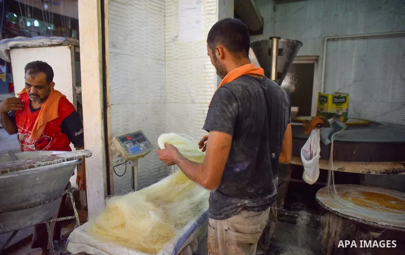 An Egyptian vendor prepares a traditional sweets known as "Konafa" on the Muslim holy fasting month of Ramadan at market in Cairo, Egypt, on June 10, 2017. Ramadan is sacred to Muslims because it is during that month tha...