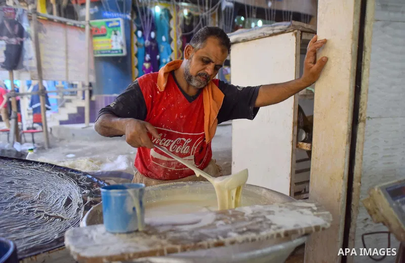 An Egyptian vendor prepares a traditional sweets known as "Konafa" on the Muslim holy fasting month of Ramadan at market in Cairo, Egypt, on June 10, 2017. Ramadan is sacred to Muslims because it is during that month tha...