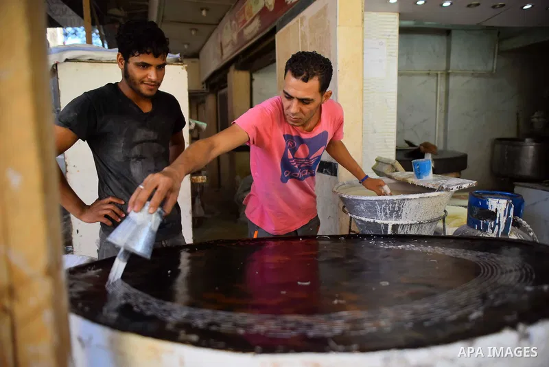An Egyptian vendor prepares a traditional sweets known as "Konafa" on the Muslim holy fasting month of Ramadan at market in Cairo, Egypt, on June 10, 2017. Ramadan is sacred to Muslims because it is during that month tha...