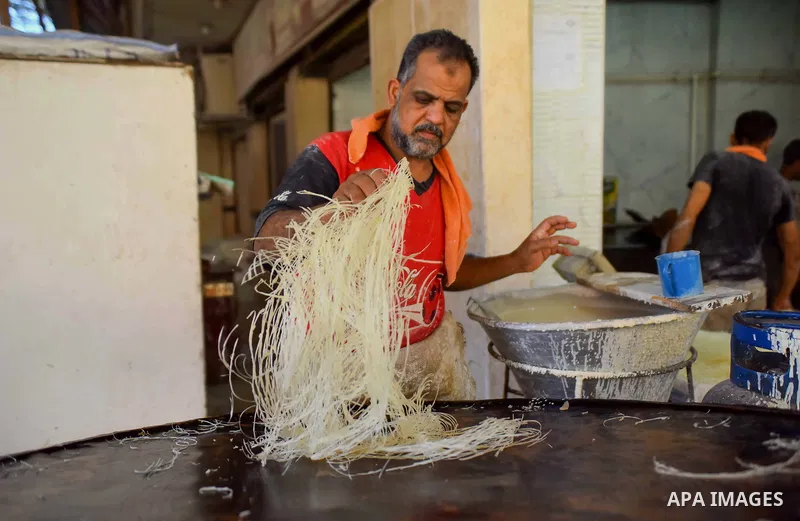 An Egyptian vendor prepares a traditional sweets known as "Konafa" on the Muslim holy fasting month of Ramadan at market in Cairo, Egypt, on June 10, 2017. Ramadan is sacred to Muslims because it is during that month tha...