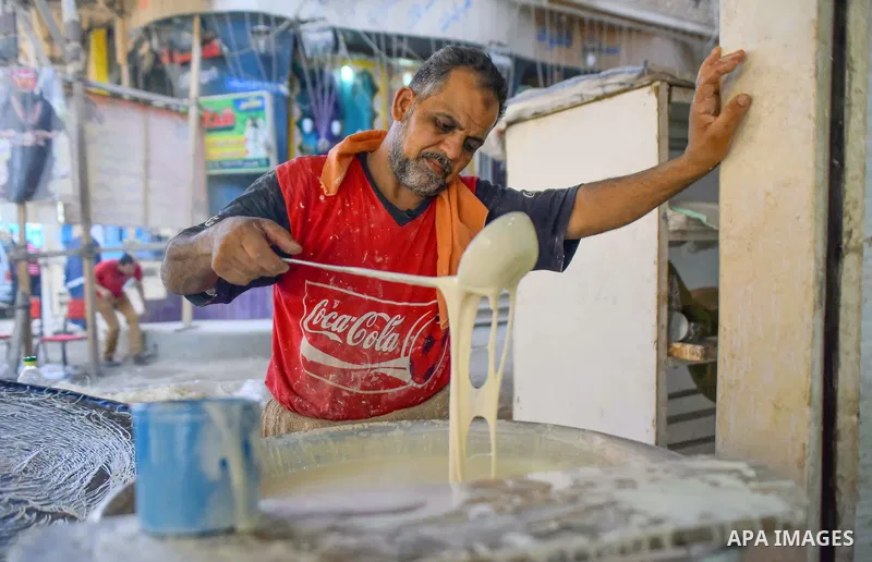 An Egyptian vendor prepares a traditional sweets known as "Konafa" on the Muslim holy fasting month of Ramadan at market in Cairo, Egypt, on June 10, 2017. Ramadan is sacred to Muslims because it is during that month tha...