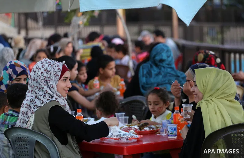 A picture taken on June 11, 2017 shows Palestinian Muslims eat their Iftar meal as they break their fast during the holy fasting month of Ramadan, at a park in Gaza city. Ramadan is sacred to Muslims because it is during...