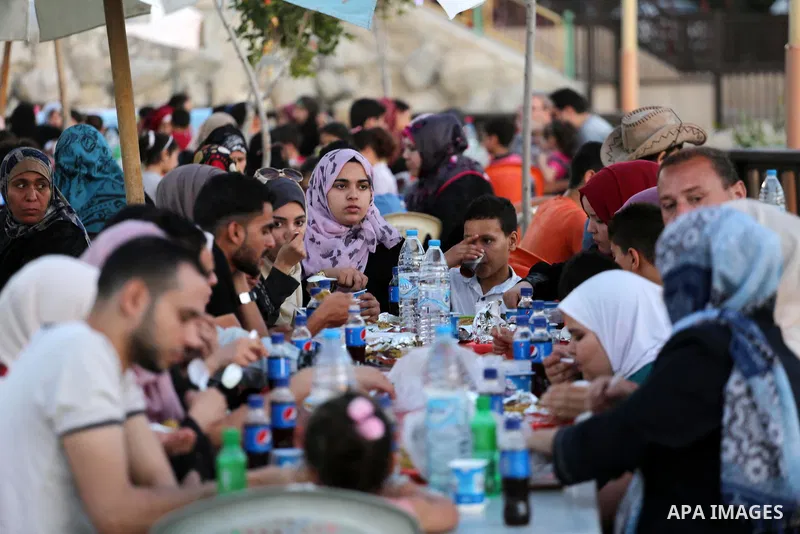 A picture taken on June 11, 2017 shows Palestinian Muslims eat their Iftar meal as they break their fast during the holy fasting month of Ramadan, at a park in Gaza city. Ramadan is sacred to Muslims because it is during...