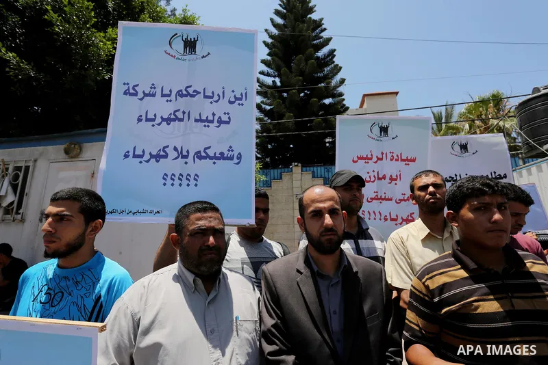 Palestinians hold placards during a protest against power cut in front of the high commissioner for human rights headquarters in Gaza city on June 13, 2017. Photo by Ashraf Amra