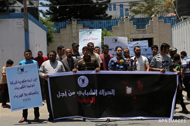 Palestinians hold placards during a protest against power cut in front of the high commissioner for human rights headquarters in Gaza city on June 13, 2017. Photo by Ashraf Amra