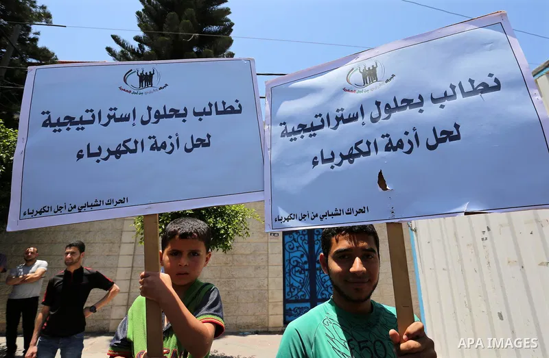Palestinians hold placards during a protest against power cut in front of the high commissioner for human rights headquarters in Gaza city on June 13, 2017. Photo by Ashraf Amra