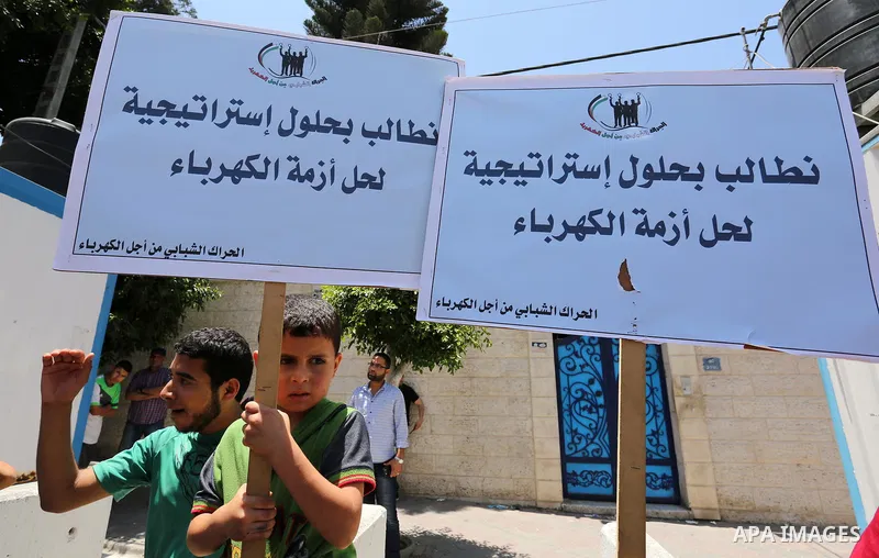 Palestinians hold placards during a protest against power cut in front of the high commissioner for human rights headquarters in Gaza city on June 13, 2017. Photo by Ashraf Amra
