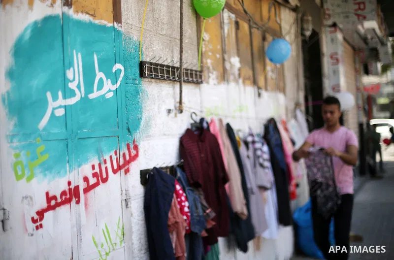 A Palestinian youth attaches second hand clothes on the wall at street for poor people, on the Muslim holy fasting month of Ramadan, on Gaza city on June 14, 2017. Ramadan is sacred to Muslims because it is during that m...
