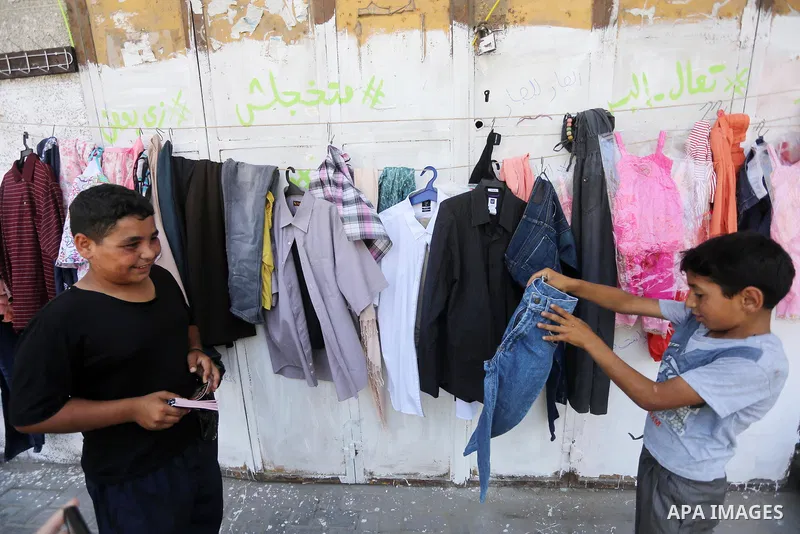 Palestinian boys look at second hand clothes attached on the wall at street for poor people, on the Muslim holy fasting month of Ramadan, on Gaza city on June 14, 2017. Ramadan is sacred to Muslims because it is during t...