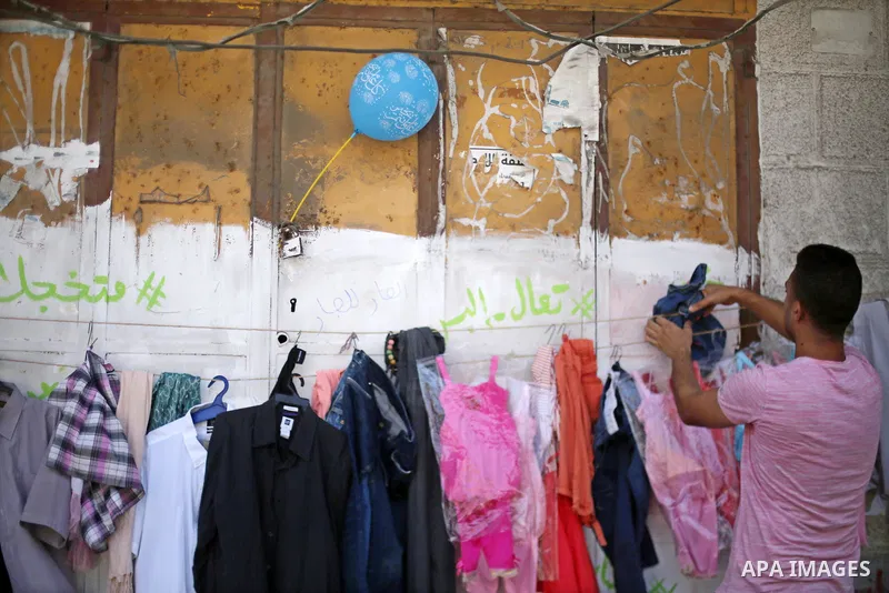 A Palestinian youth attaches second hand clothes on the wall at street for poor people, on the Muslim holy fasting month of Ramadan, on Gaza city on June 14, 2017. Ramadan is sacred to Muslims because it is during that m...