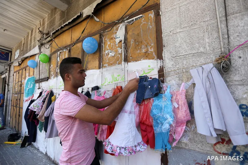 A Palestinian youth attaches second hand clothes on the wall at street for poor people, on the Muslim holy fasting month of Ramadan, on Gaza city on June 14, 2017. Ramadan is sacred to Muslims because it is during that m...