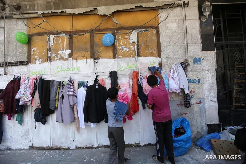 Palestinian boys look at second hand clothes attached on the wall at street for poor people, on the Muslim holy fasting month of Ramadan, on Gaza city on June 14, 2017. Ramadan is sacred to Muslims because it is during t...