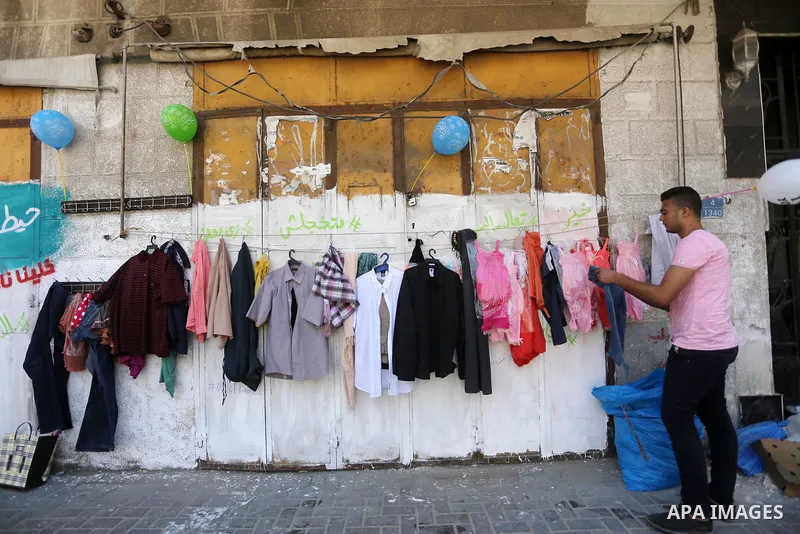 A Palestinian youth attaches second hand clothes on the wall at street for poor people, on the Muslim holy fasting month of Ramadan, on Gaza city on June 14, 2017. Ramadan is sacred to Muslims because it is during that m...