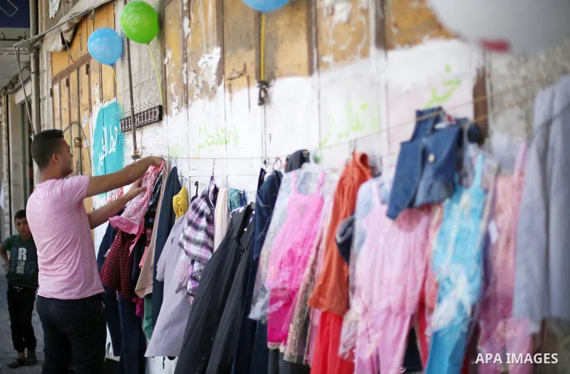 A Palestinian youth attaches second hand clothes on the wall at street for poor people, on the Muslim holy fasting month of Ramadan, on Gaza city on June 14, 2017. Ramadan is sacred to Muslims because it is during that m...