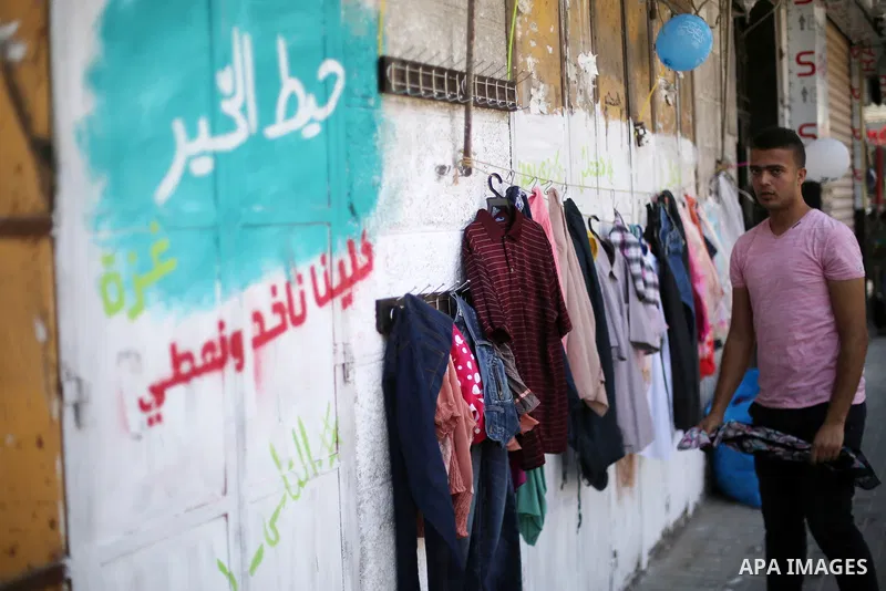 A Palestinian youth attaches second hand clothes on the wall at street for poor people, on the Muslim holy fasting month of Ramadan, on Gaza city on June 14, 2017. Ramadan is sacred to Muslims because it is during that m...