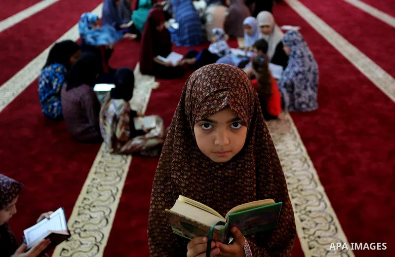 A Palestinian girl reads a copy of the Koran, Islam's holiest book, on the Muslim holy fasting month of Ramadan, at Hamad Mosque in Khan Younis in the southern Gaza Strip, June 14, 2017. Ramadan is sacred to Muslims beca...