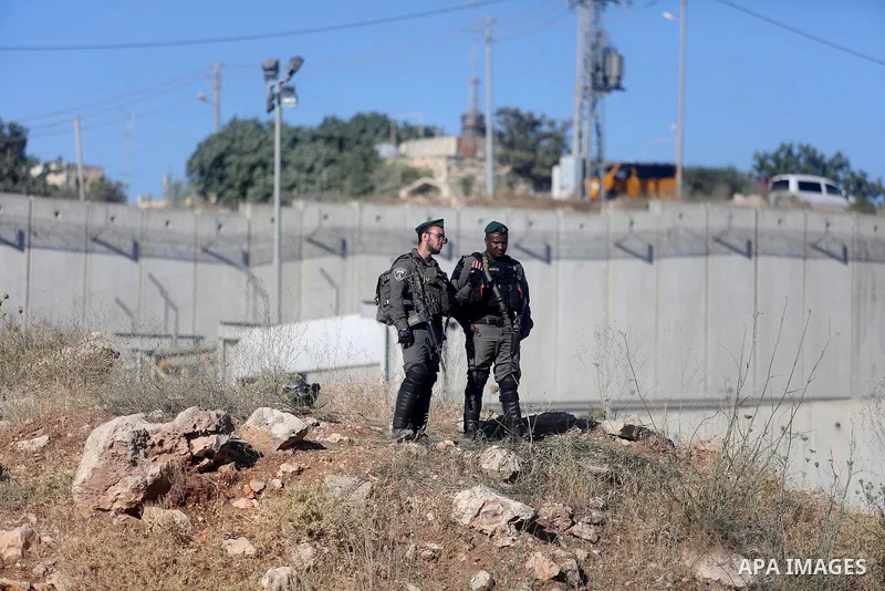 Israeli security forces stand facing Palestinian as they make their way through the Israeli Qalandia checkpoint, in the occupied West Bank between Ramallah and Jerusalem, to attend Friday prayer of the holy fasting month...