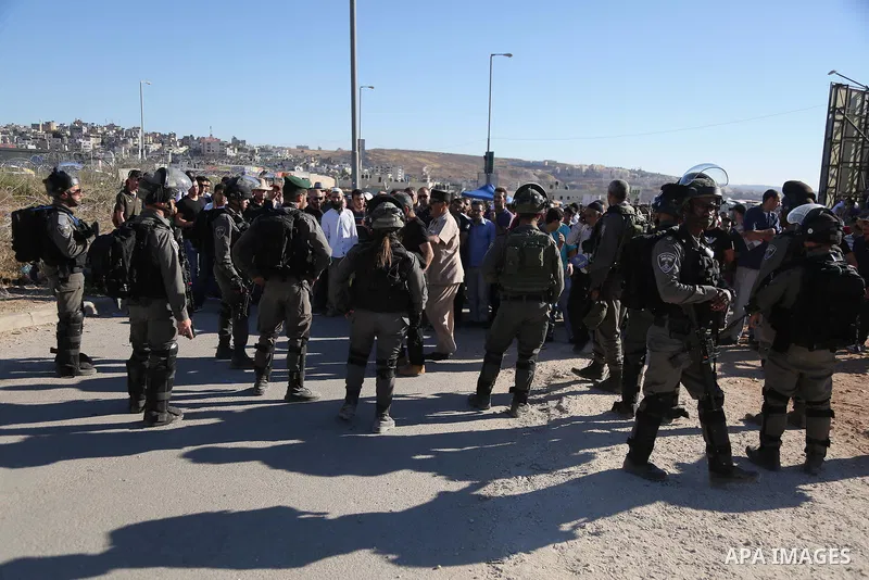 Israeli security forces stand facing Palestinian as they make their way through the Israeli Qalandia checkpoint, in the occupied West Bank between Ramallah and Jerusalem, to attend Friday prayer of the holy fasting month...