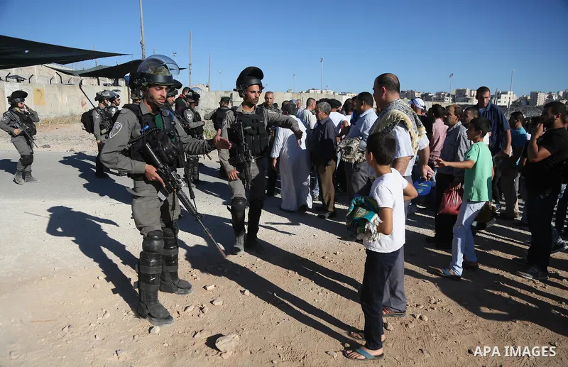 Israeli security forces stand facing Palestinian as they make their way through the Israeli Qalandia checkpoint, in the occupied West Bank between Ramallah and Jerusalem, to attend Friday prayer of the holy fasting month...