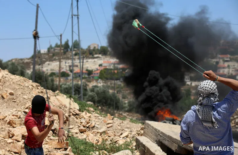 A Palestinian protester uses a slingshot to hurl stones towards Israeli security forces during clashes following a demonstration against the expropriation of Palestinian land by Israel in the village of Kfar Qaddum, near...