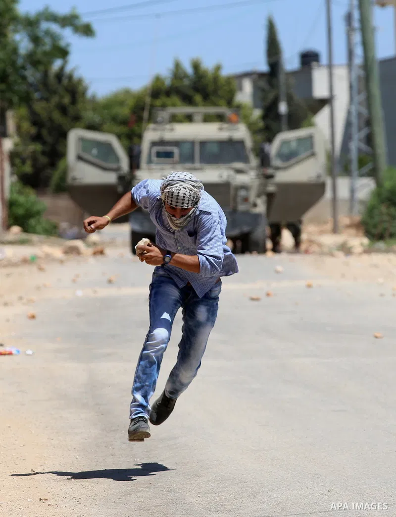 A Palestinian protester runs as he hurls stones towards Israeli security forces during clashes following a demonstration against the expropriation of Palestinian land by Israel in the village of Kfar Qaddum, near Nablus,...