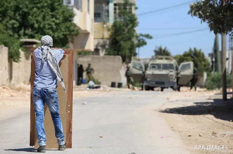 A Palestinian protester hurls stones towards Israeli security forces during clashes following a demonstration against the expropriation of Palestinian land by Israel in the village of Kfar Qaddum, near Nablus, in the occ...
