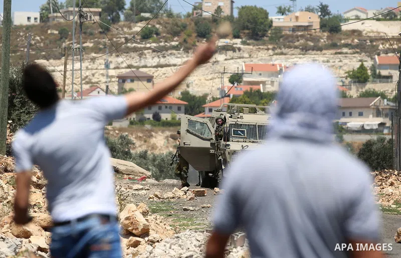A Palestinian protester hurls stones towards Israeli security forces during clashes following a demonstration against the expropriation of Palestinian land by Israel in the village of Kfar Qaddum, near Nablus, in the occ...