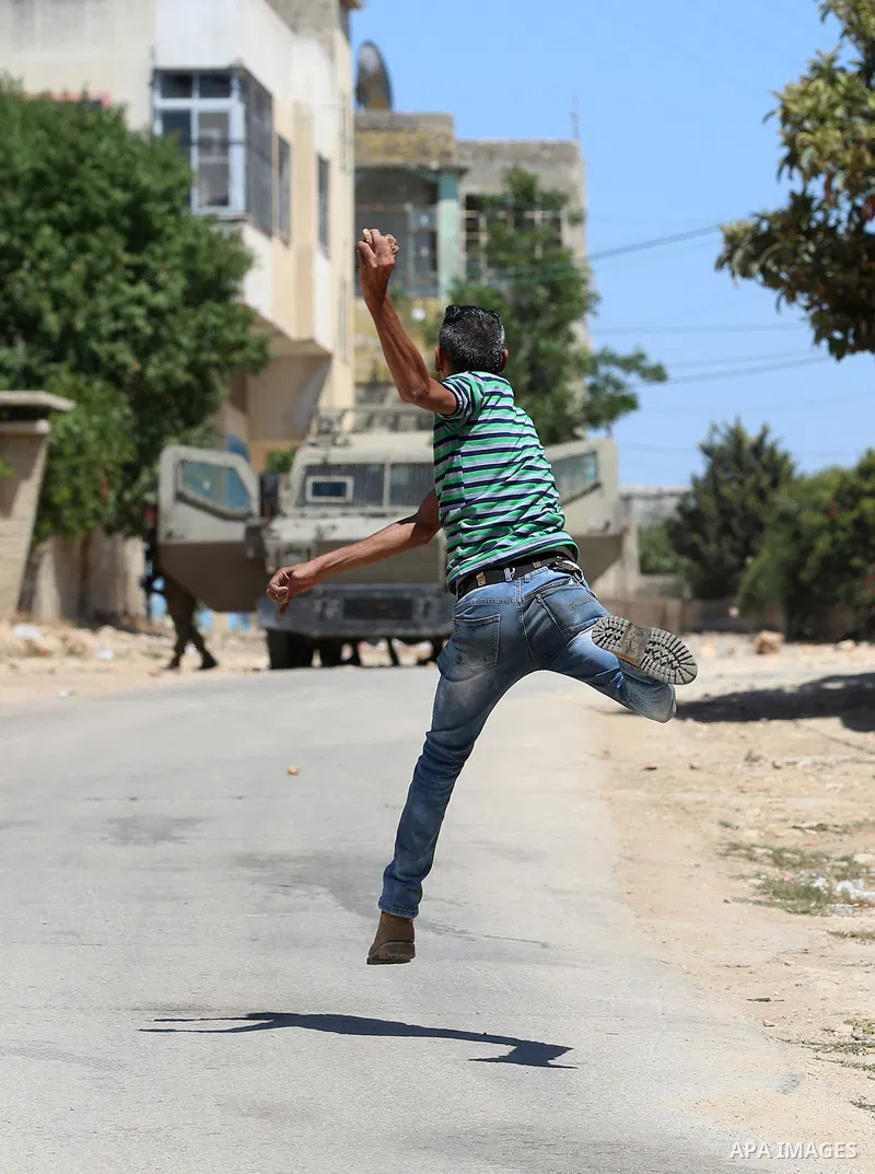 A Palestinian protester hurls stones towards Israeli security forces during clashes following a demonstration against the expropriation of Palestinian land by Israel in the village of Kfar Qaddum, near Nablus, in the occ...