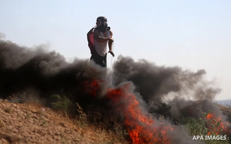 A Palestinian protester uses a slingshot to hurl stones towards Israeli security forces during clashes following a demonstration against the blockade on the Gaza Strip, near the border fence east of Jabalia refugee camp...
