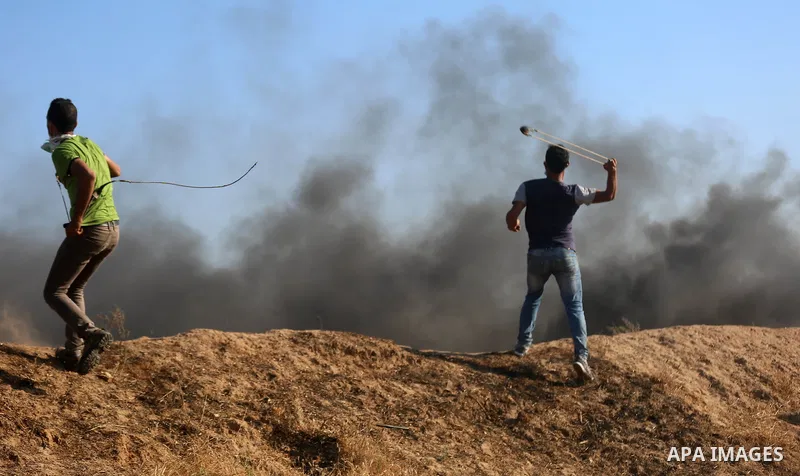 A Palestinian protester uses a slingshot to hurl stones towards Israeli security forces during clashes following a demonstration against the blockade on the Gaza Strip, near the border fence east of Jabalia refugee camp...