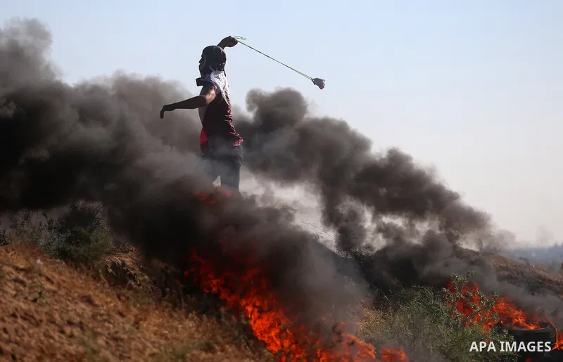 A Palestinian protester uses a slingshot to hurl stones towards Israeli security forces during clashes following a demonstration against the blockade on the Gaza Strip, near the border fence east of Jabalia refugee camp...