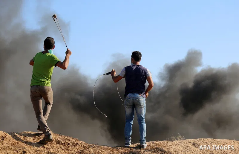 A Palestinian protester uses a slingshot to hurl stones towards Israeli security forces during clashes following a demonstration against the blockade on the Gaza Strip, near the border fence east of Jabalia refugee camp...