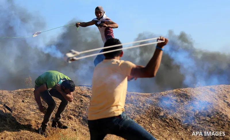 A Palestinian protester uses a slingshot to hurl stones towards Israeli security forces during clashes following a demonstration against the blockade on the Gaza Strip, near the border fence east of Jabalia refugee camp...