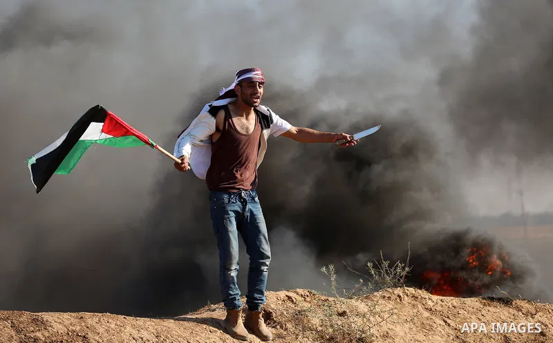 A Palestinian protester waves the national during clashes with Israeli security forces following a protest near the border fence east of Jabalia refugee camp, against the blockade on the Gaza Strip on June 16, 2017. Phot...