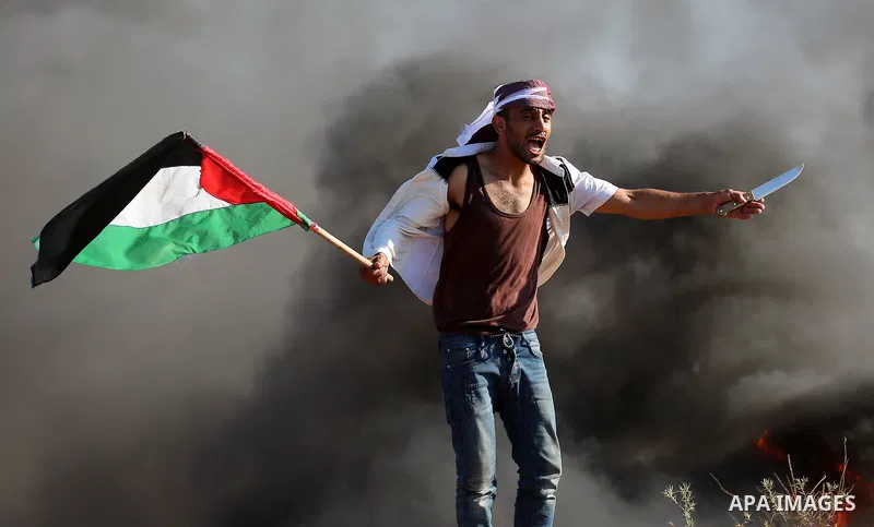 A Palestinian protester waves the national during clashes with Israeli security forces following a protest near the border fence east of Jabalia refugee camp, against the blockade on the Gaza Strip on June 16, 2017. Phot...
