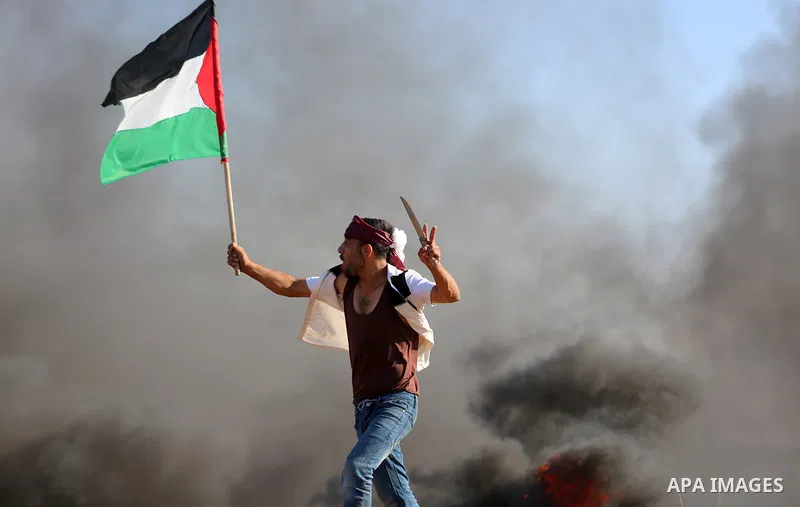 A Palestinian protester waves the national during clashes with Israeli security forces following a protest near the border fence east of Jabalia refugee camp, against the blockade on the Gaza Strip on June 16, 2017. Phot...