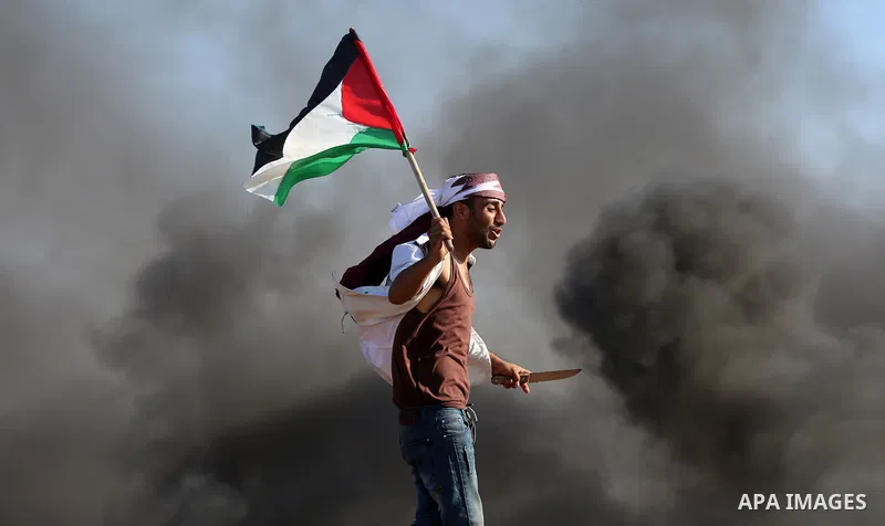 A Palestinian protester waves the national during clashes with Israeli security forces following a protest near the border fence east of Jabalia refugee camp, against the blockade on the Gaza Strip on June 16, 2017. Phot...