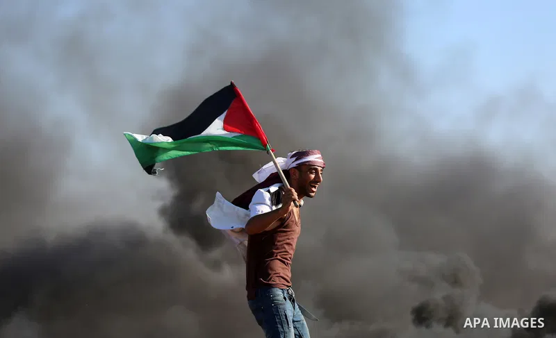A Palestinian protester waves the national during clashes with Israeli security forces following a protest near the border fence east of Jabalia refugee camp, against the blockade on the Gaza Strip on June 16, 2017. Phot...