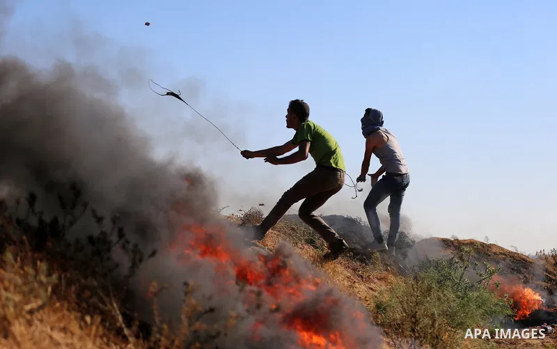 A Palestinian protester uses a slingshot to hurl stones towards Israeli security forces during clashes following a demonstration against the blockade on the Gaza Strip, near the border fence east of Jabalia refugee camp...
