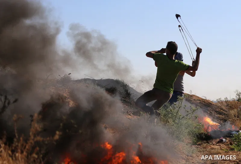 A Palestinian protester uses a slingshot to hurl stones towards Israeli security forces during clashes following a demonstration against the blockade on the Gaza Strip, near the border fence east of Jabalia refugee camp...