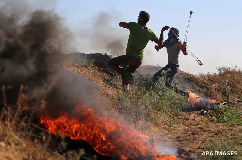 A Palestinian protester uses a slingshot to hurl stones towards Israeli security forces during clashes following a demonstration against the blockade on the Gaza Strip, near the border fence east of Jabalia refugee camp...
