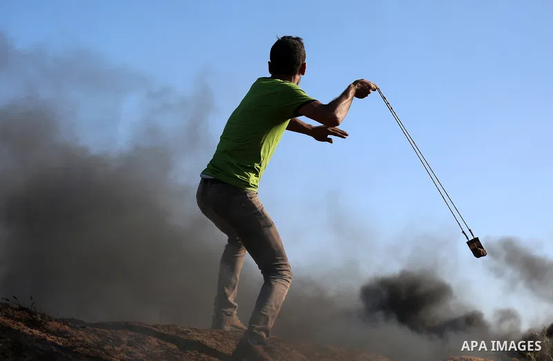 A Palestinian protester uses a slingshot to hurl stones towards Israeli security forces during clashes following a demonstration against the blockade on the Gaza Strip, near the border fence east of Jabalia refugee camp...