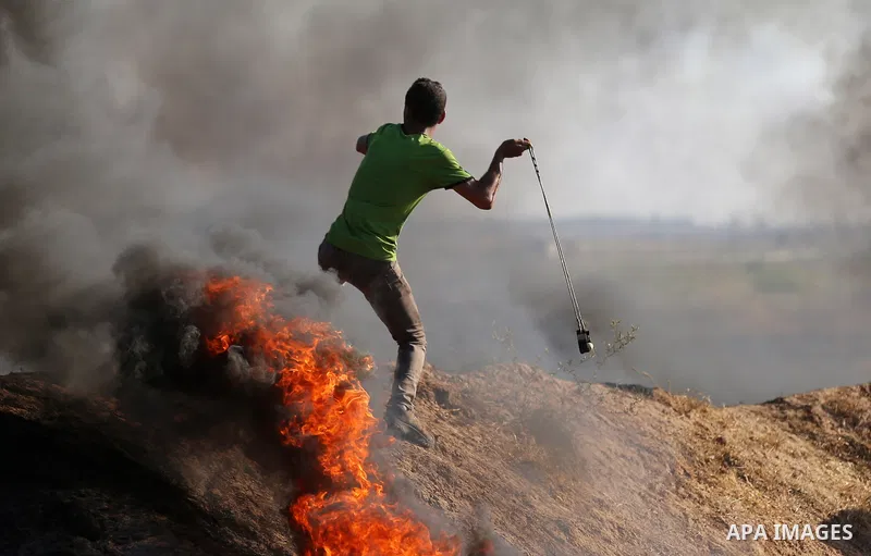 A Palestinian protester uses a slingshot to hurl stones towards Israeli security forces during clashes following a demonstration against the blockade on the Gaza Strip, near the border fence east of Jabalia refugee camp...