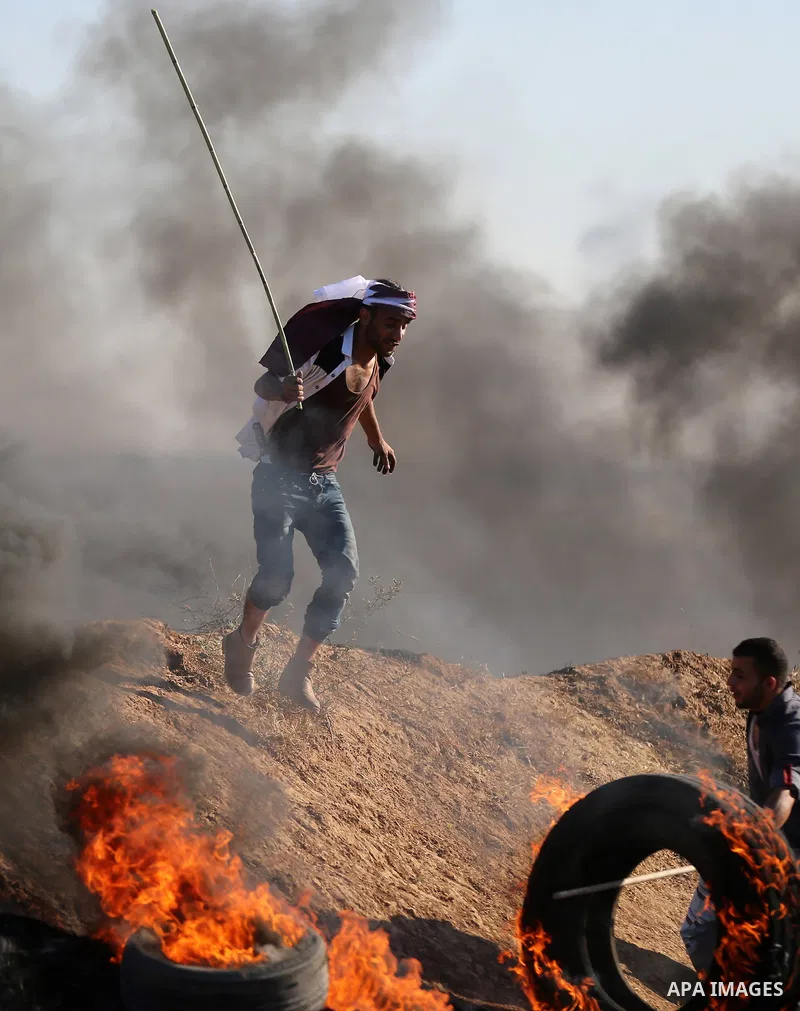 Palestinian protesters take cover during clashes with Israeli security forces following a demonstration against the blockade on the Gaza Strip, near the border fence east of Jabalia refugee camp on June 16, 2017. Photo b...