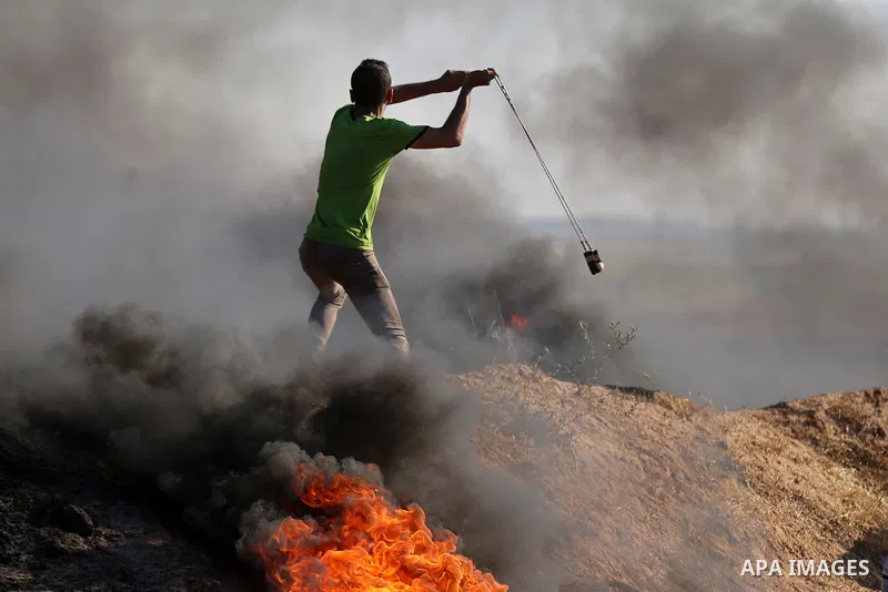 A Palestinian protester uses a slingshot to hurl stones towards Israeli security forces during clashes following a demonstration against the blockade on the Gaza Strip, near the border fence east of Jabalia refugee camp...