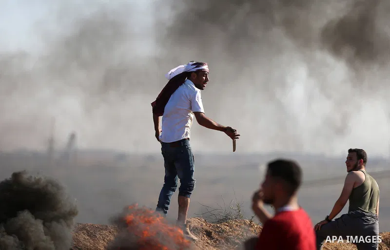 Palestinian protesters take cover during clashes with Israeli security forces following a demonstration against the blockade on the Gaza Strip, near the border fence east of Jabalia refugee camp on June 16, 2017. Photo b...